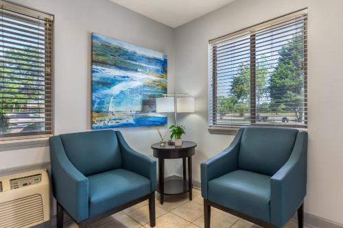 two blue chairs and a table in a room with windows at HomeTowne Studios & Suites by Red Roof Greensboro in Greensboro