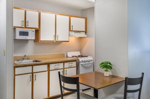 a small kitchen with a table and a sink at HomeTowne Studios & Suites by Red Roof Greensboro in Greensboro