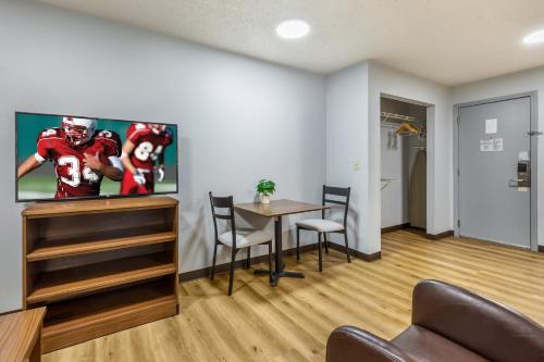 a living room with a table and a football player on the wall at HomeTowne Studios & Suites by Red Roof Greensboro in Greensboro