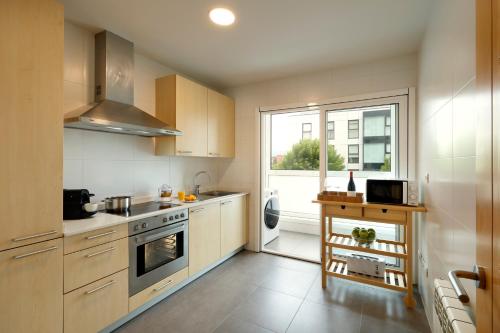 Una cocina con gabinetes blancos y una ventana grande. en Vita Homes by Upper Luxury Housing, en Santiago de Compostela