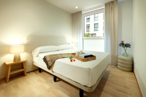 Una habitación blanca con una cama y una ventana en Vita Homes by Upper Luxury Housing, en Santiago de Compostela