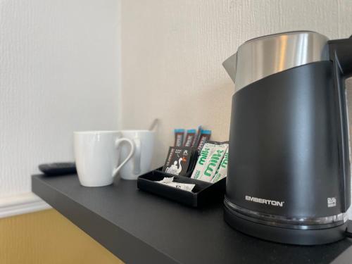 a coffee maker sitting on a black counter with cups at Wedgwood Hotel, Bay Room in Llandudno