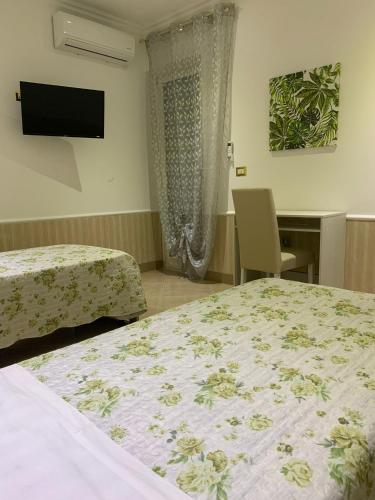 ein Schlafzimmer mit zwei Betten, einem Schreibtisch und einem Fernseher in der Unterkunft Corte Vena Palace in Bianco