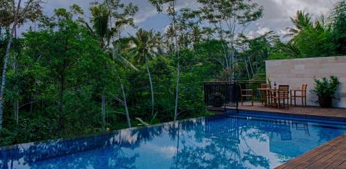 a swimming pool with a table and chairs on a deck at River Sakti Ubud by Prasi in Ubud