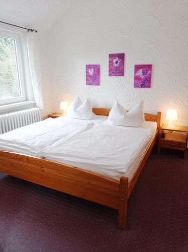 a bedroom with a large bed with white sheets and pillows at Pension Sonnenhof in Braunlage
