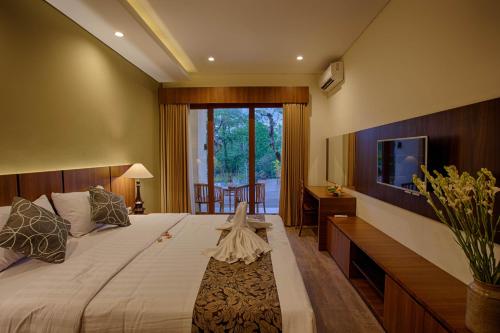 a bedroom with a large bed and a television at River Sakti Ubud by Prasi in Ubud