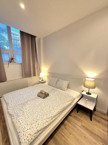 a white bedroom with a bed and two lamps at Apartmány v srdci Ružinova in Trnávka