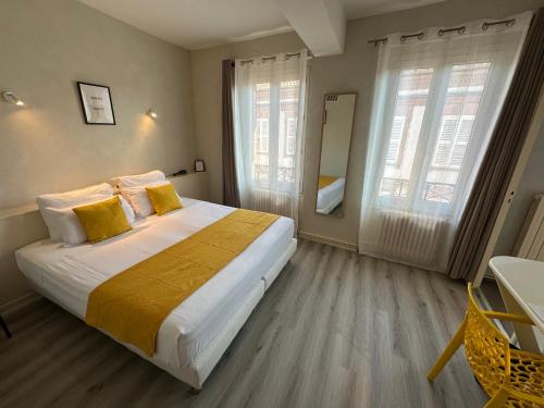 a bedroom with a large bed and two windows at Hotel Chiffre in Albi