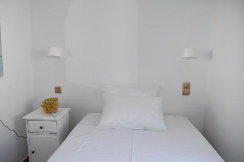 a white bedroom with a bed and a nightstand at Anemi in Spetses