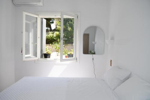 a white room with a bed and two windows at Anemi in Spetses