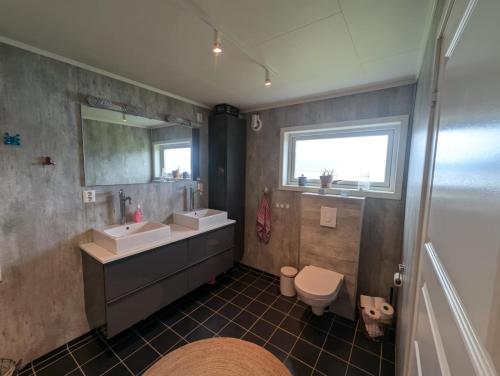 a bathroom with two sinks and a toilet at Cozy familyhouse with free parking & fantastic view in Tromsø