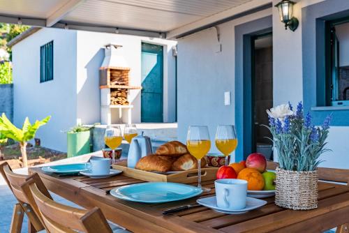 a wooden table with food and glasses of wine at Casa D'Avó Bela in Arco da Calheta