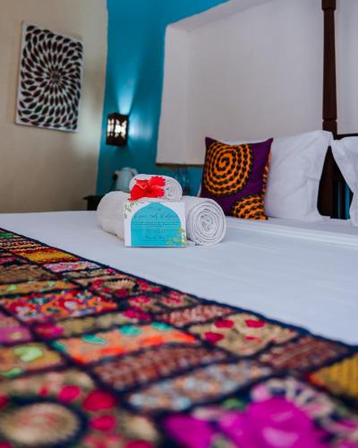 a bed with a pile of towels and a pile of pillows at Emerald Palm Boutique Hotel in Zanzibar City