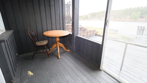 a wooden table and chair on a porch with a window at Algonquin Lakeside Inn in Dwight