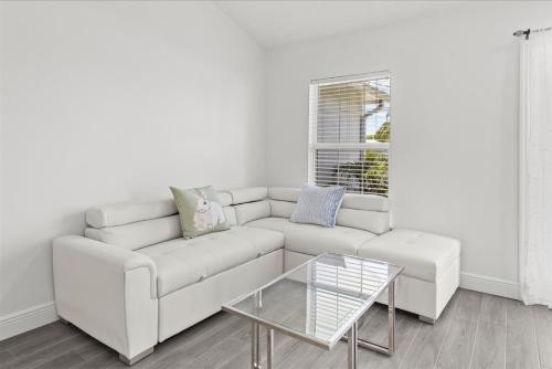 a white living room with a white couch and a glass table at Coosa Dr in Port Saint Lucie