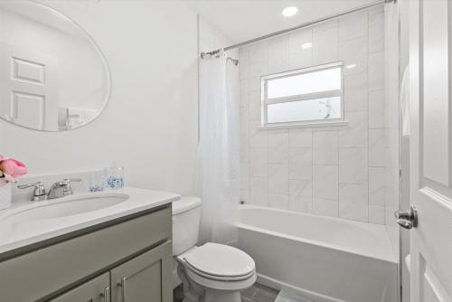 a white bathroom with a toilet and a sink at Coosa Dr in Port Saint Lucie