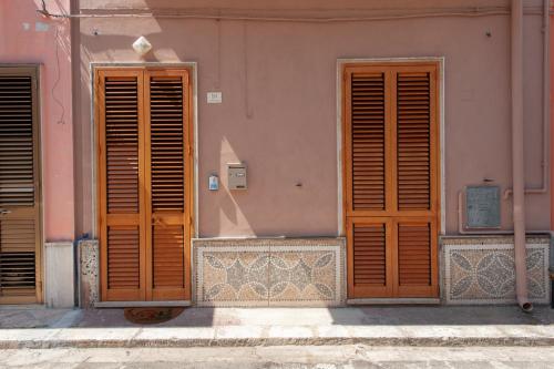 two wooden doors on the side of a pink building at Salento dream in Trepuzzi