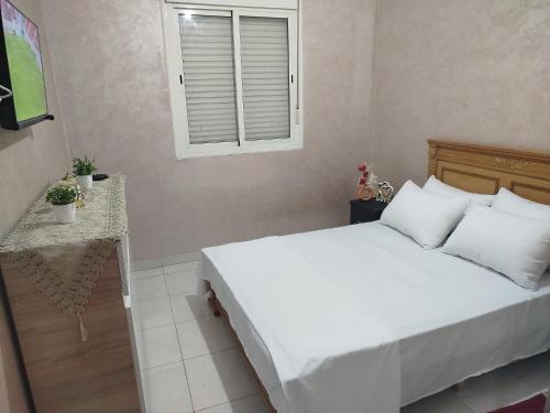 a bedroom with a white bed and a window at app entre aéroport M5 et nearshore sidi maarouf in Bouskoura