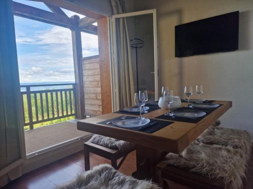 a wooden table with wine glasses and a balcony at Lumières du Lac in Lugrin