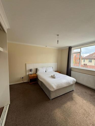 a bedroom with a white bed and a window at Sea Side Hotel in Skegness
