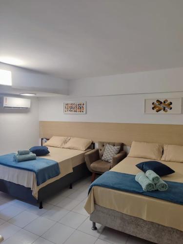 a room with two beds and a chair in it at Flat completo 50m da Praia de Tambaú com vista Mar no Terraço e Piscina in João Pessoa