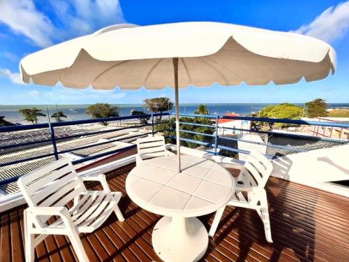 a table and chairs on a deck with an umbrella at Flat completo 50m da Praia de Tambaú com vista Mar no Terraço e Piscina in João Pessoa
