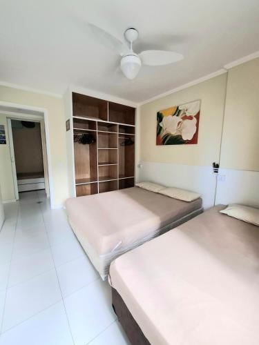 two beds in a room with a ceiling fan at Pitangueiras - Shopping in Guarujá
