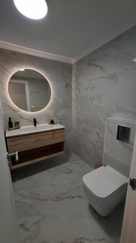 Un baño con inodoro, lavabo y espejo. en Luxury apartment, en La Tejita