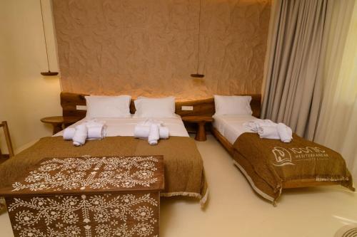 two beds in a room with white towels on them at Iconic Mediterranean Hotel in Dhërmi