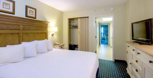 a bedroom with a white bed and a flat screen tv at Compass Cove in Myrtle Beach