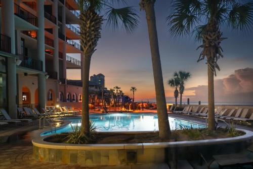 a swimming pool with palm trees and a hotel at The Oasis at Orange Beach Condos by Hosteeva in Orange Beach