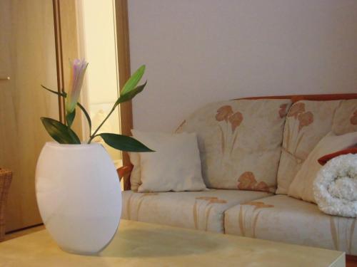 a white vase sitting on a table next to a couch at SchlossparkFerienwohnungen Rheinsberg mit Garten in Rheinsberg