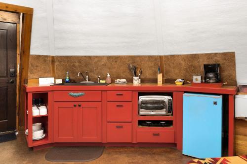 a kitchen with red cabinets and a blue refrigerator at Tipis on the Guadalupe in New Braunfels
