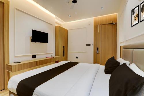 a bedroom with a large white bed and a television at Hotel O Nirmal Restaurant Bar Banquet & Rooms Faridapur in Alambagh