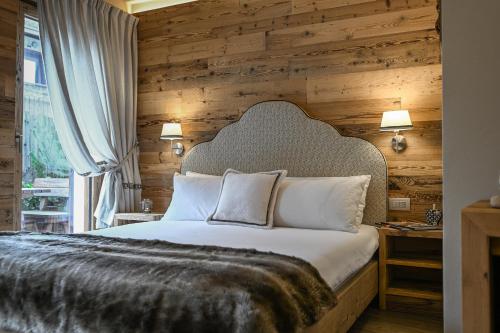 a bedroom with a large bed with a wooden wall at Al Baitin - Charme & Nature - in Santa Caterina Valfurva