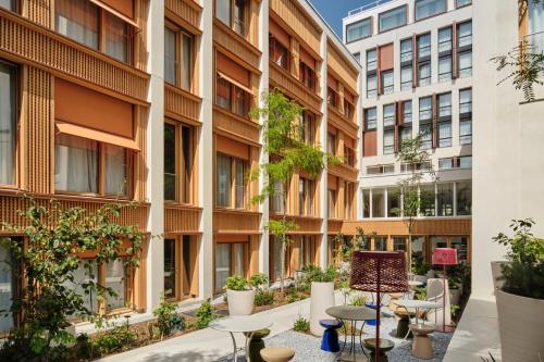 an internal courtyard of a building with tables and plants at TRIBE Paris Pantin in Pantin