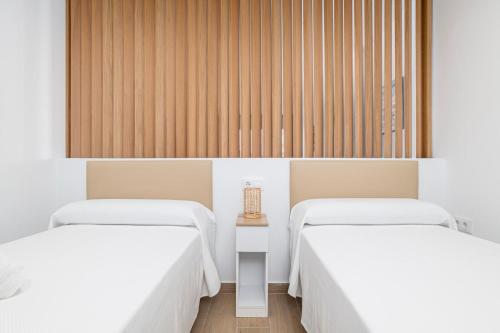 two beds in a hotel room with white sheets at Apartamentos Almadraba in Zahara de los Atunes