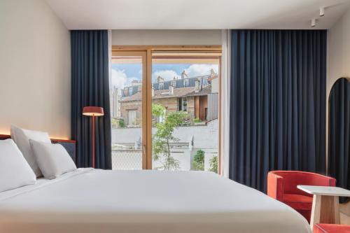a bedroom with a large bed and a large window at TRIBE Paris Pantin in Pantin