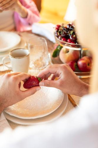 a person holding a strawberry on a plate on a table at Etna Glamping in Milo