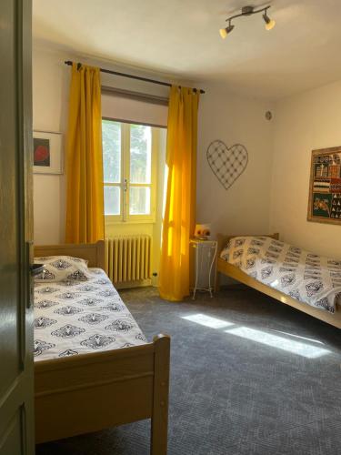 a bedroom with two beds and a window with yellow curtains at Camelia Casa Vacanze in Palazzo Canavese