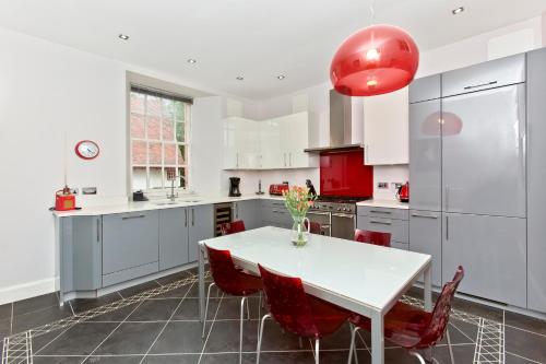a kitchen with a white table and red chairs at Luxury-3-bedroom Ramsay Garden Apartment next to Edinburgh Castle in Edinburgh