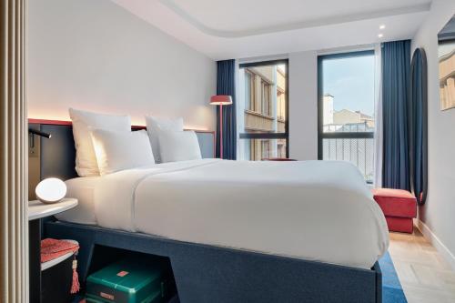a bedroom with a white bed and a balcony at TRIBE Paris Pantin in Pantin