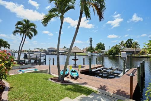 a dock with a boat on the water with palm trees at Cape Serenity- Luxury Waterfront Villa with Kayaks and Bikes in Cape Coral