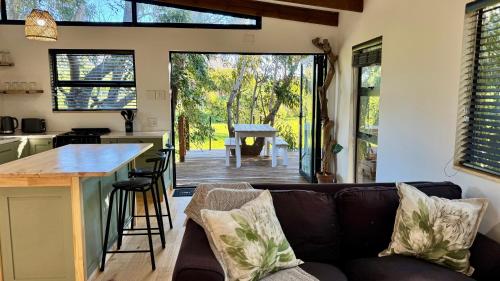 a living room with a couch and a kitchen and a table at Blue Gum Tree Cottage in Dagbreek