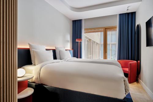 a bedroom with a large bed and a red chair at TRIBE Paris Pantin in Pantin