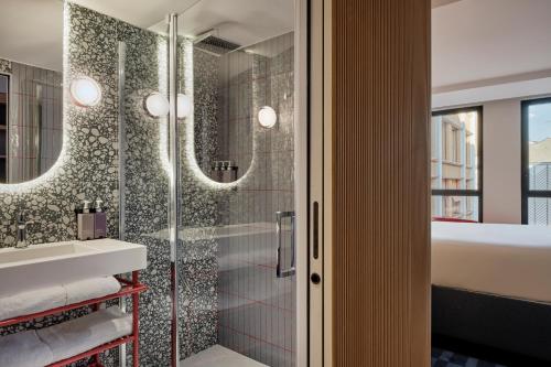 a bathroom with a shower and a sink and mirror at TRIBE Paris Pantin in Pantin