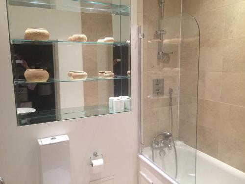 a bathroom with a shower and a glass shower backdoor at The Bromptons, Luxury South Kensington Apartment in London