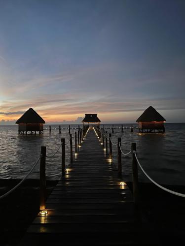 a pier with umbrellas and lights on the water at LOB LOB Cabañas in Dzilam de Bravo