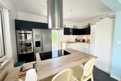 una cucina con un tavolo di legno e sedie bianche di Maison lumineuse avec jardin à 50m de la mer a Larmor-Plage