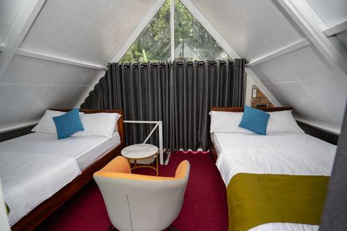 a attic bedroom with two beds and a chair at The Tranquil Cabana - kandy in Rattanadeniya